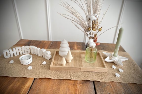 Tischläufer dekoriert mit verschiedenen Tannenbäumen, Glasvase mit Trockenblumen und Sternkerzenhalter mit grüner Kerze