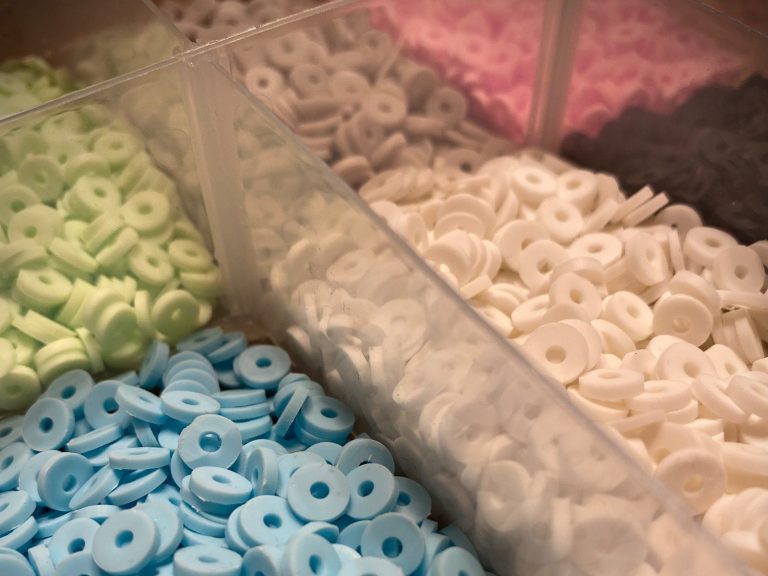 Bunte runde Perlen in verschiedenen Farben in durchsichtigen Behältern.