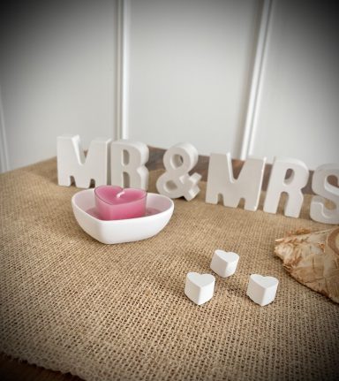Weiße Buchstaben Mr & Mrs und eine herzförmige Schale mit Herzteelicht