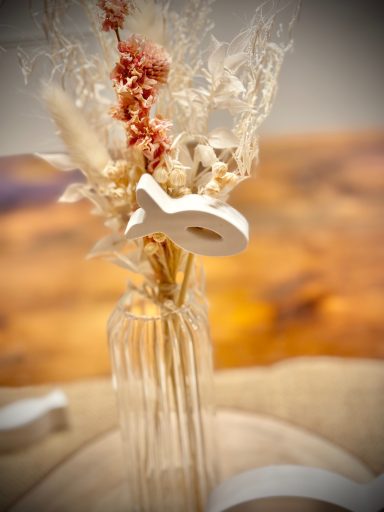 Glasvase mit Trockenblumen und Stecker in Fischform
